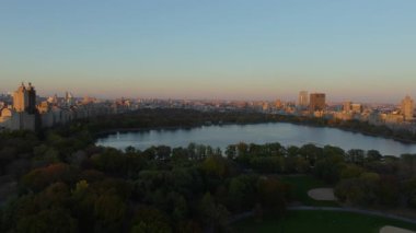 Havadan alınan görüntüler, New York şehrinin silueti tarafından çerçevelenen ve günbatımında sakin bir şehir manzarası yaratan Central Park rezervuarını ve çeşmesini vurguluyor..