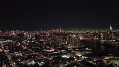 Gece Queens 'in büyüleyici manzarası, East River' ı gözler önüne seriyor ve Manhattan 'ın göbeğinin parıldayan silueti uzaklarda.