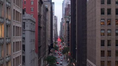 Manhattan şehir merkezinin pencerelerinin hava manzarası, alacakaranlık sırasında yüksek binaların altındaki araç hareketlerini takip etmek, şehir merkezindeki mimari ihtişamı vurgulamak..