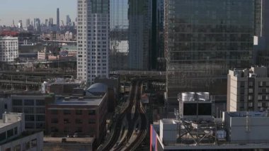 Modern gökdelenlerin arasında yükseltilmiş metro raylarının yer aldığı şehir manzarası, Long Island City 'deki karmaşık taşıma altyapısını gözler önüne seriyor..