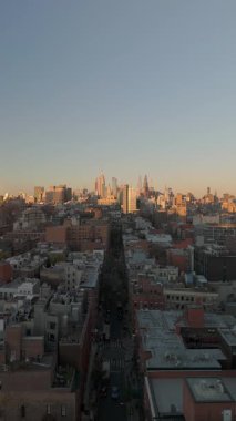 Günbatımı sıcak renklerde gökdelenleri yıkarken dikey hava manzarası Midtown Manhattan, New York Caddesi 'ni gösteriyor. Uzak Empire State Binası 'nı da içeren canlı bir siluet..