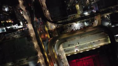 Hava manzarası, gece yoğun New York sokaklarını gözler önüne seriyor, gezen arabaları vurguluyor ve ışıldayan şehir manzarasında gökdelenleri aydınlatıyor..