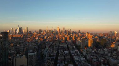 New York 'u çevreleyen sıcak güneş ışığının kuşbakışı manzarası Manhattan şehir merkezindeki binalar, altın saat boyunca gökyüzünü canlı renklerle boyuyor..
