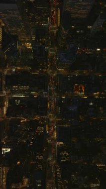 Aydınlatılmış Manhattan sokakları gece yavaş çekimde canlanıyor, canlı ışıklar, yoğun trafik, ikonik New York gökdelenleri taşınabilir dost formatında resmedilmiş.