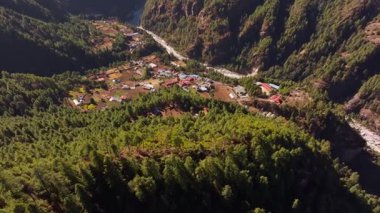 Huzurlu Himalaya köyü Everest yakınlarındaki Monjo, yemyeşil ormanı ve kıvrımlı nehri kucaklıyor, el değmemiş Nepliler 'in el değmemiş dağ manzarasını yakalıyor..