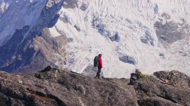 Deneyimli dağcı Himalayalar 'ın kayalık tepelerini aşıyor, geniş bir Ngozumpa buzuluna bakıyor Everest Dağı' nın silueti dramatik alp manzarasına karşı..