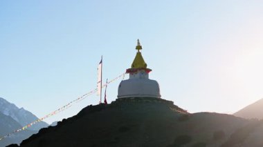 Himalaya yamacına tünemiş beyaz bir budist, Dingboche 'daki manzarayı aydınlatan gün ışığı bayrakları dalgalanıyor..