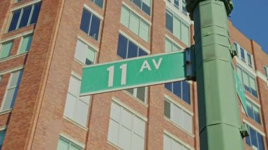 Chelsea Mahallesi 'nin ortasında duran 11. Cadde tabelası New York' taki mavi gökyüzüne karşı Manhattan kentsel manzarasını yakalıyor..