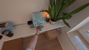 Modern bir mutfakta kahve hazırlayan birinin bakış açısı açık mavi bir espresso kahve makinesi, Berlin, 5.8.2025.