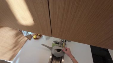 Pencere kenarındaki bitki yetiştiren adam, minimalist iç kısımlardan geçen güneş ışığı, çevre dostu ev bahçesi yaşam tarzı, Berlin, 5.8.2025.