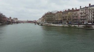 Hava manzarası Lyons 'un soğuk mevsim manzarasını yakalıyor, Saone nehri yapraksız ağaçların yanından geçiyor, kentsel siluetler bulutlu siluetleri sessiz mevsimsel tonlarda çerçeveliyor..