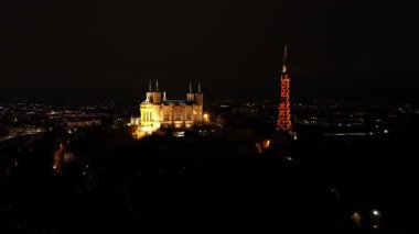 Aydınlatılmış Fourviere Bazilikası ve tepenin havadan görünüşü, Lyon 'da gece vakti şehrin arka planına sahip metalik televizyon kulesi.
