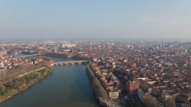Toulouse şehir manzarasını vurgulayan hava manzarası, Pont Neuf köprüsü yakınlarında kıvrılan Garonne nehri, tarihi kent mimarisi ve canlı şehir manzarasını gözler önüne seriyor..