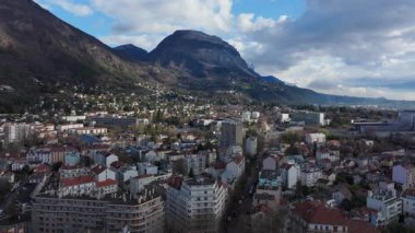 Panoramik hava perspektifi Dent de Crolle ile çevrili Grenoble şehir manzarasını yakalıyor, kentsel yayılma, yerleşim bölgeleri, bulutlu gökyüzü altında altyapı.