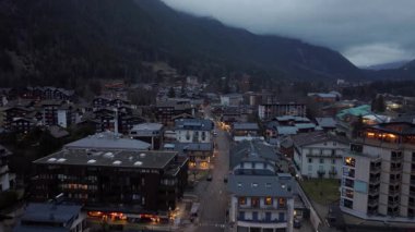 Chamonix şehri alacakaranlıkta parlıyor, Mont Blanc yakınlarındaki Fransız Alplerine yerleşmiş, büyük bir turizm beldesinde sakin bir dağ manzarası sunuyor..