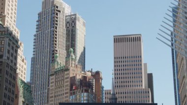 Park Row Binası, Manhattan 'da yükselen modern gökdelenlerin ortasında parlak mavi gökyüzünün altında dinamik şehir manzarası..