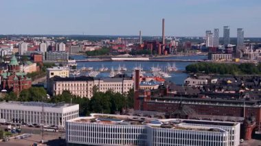 Helsinki 'nin ufuk çizgisini gösteren hava manzaraları, teknelerle dolu canlı bir limanı gözler önüne seriyor. Şehir hayatı çarpıcı bir mimari zeminine ve berrak mavi gökyüzüne karşı gelişiyor..