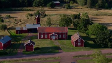 Finlandiya 'nın Aland kentinin kırsal kesimindeki geleneksel kırmızı çiftlik binalarının hava manzarası. Güneşli bir yaz gününde bir yel değirmeni dimdik ayakta.