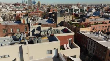 Hava görüntülerinde Williamsburg, Brooklyn 'deki çatılar, apartmanlar ve kasaba evleri görülüyor. Arabalar sokaklarda hareketli şehir atmosferi sergiliyor..