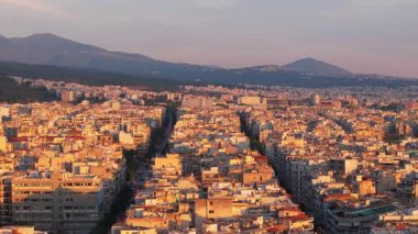 Yunanistan 'ın Selanik kentindeki Tsimiski Caddesi ve yakınlarındaki bölgelerin yer aldığı şehir manzarası. Sıcak gün batımı ışığı şehri altın sarısı bir renkle kaplar..