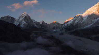 Şafak vakti Nepal 'deki kar örtülü dağların hava manzarası, Görkemli Buzul Vadisi ve Aşağıdaki Bulutlu Bulutlar.