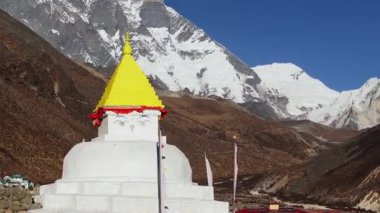 Himalayalar 'da gözlerden uzak bir Nepal köyünün insansız hava aracı görüntüsü, geleneksel binaları ve büyük karlı tepeleri vurguluyor.