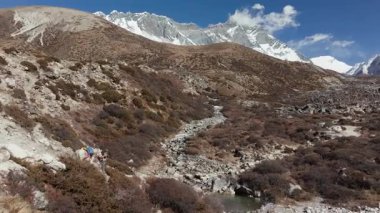 Nepal 'deki uzak bir dağ vadisinde, karlı tepelerin ortasında engebeli bir patikada at binicisinin gezindiği hava manzarası..