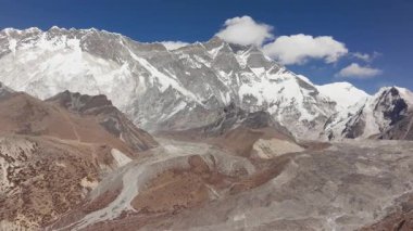 Nepal 'deki görkemli bir dağ sırasının havadan görünüşü, açık mavi gökyüzü altında karla kaplı tepeler ve buzul vadisiyle.