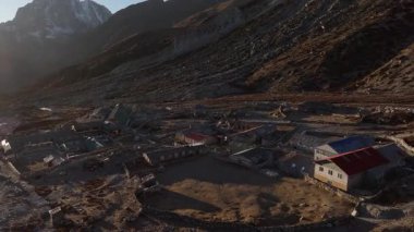 Geleneksel tasarımlar ve karlı zirvelerle dağlarda yuva yapmış sessiz bir Nepal köyüne insansız hava aracı..