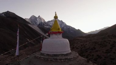 Nepal 'in Himalayaları' nda gün batımında karla kaplı görkemli dağlarla çevrili sakin bir stupanın havadan görünüşü..