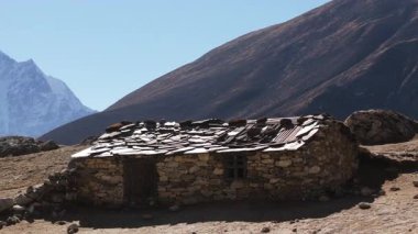 Himalayalar 'daki geleneksel bir taş binanın sabit bir görüntüsü. Arka planda karla kaplı görkemli dağlar var..