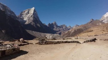 Dağlarda yuva yapmış huzurlu bir Nepal köyünün tepeden görünüşü, kültürel tasarımlar ve karla kaplı görkemli bir tepe.