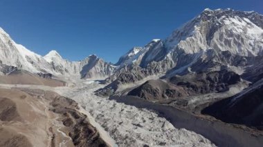 Nepal 'in Himalayalarında yuva yapmış görkemli bir buzulun havadan görünüşü, karla kaplı tepeler ve sakin bir dağ vadisi..