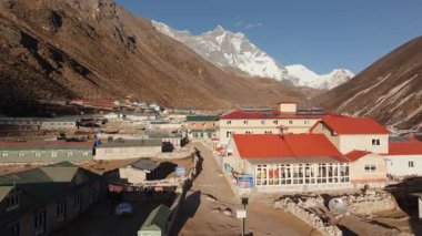 Nepal 'de ıssız bir dağ köyünün insansız hava aracı görüntüsü, kırsal binalar ve görkemli karlı bir zirve içeriyor..