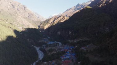 İzole bir Himalaya köyünün havadan görünüşü, taş evler ve el değmemiş bir kar sırtı sergiliyor..