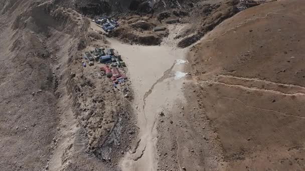 Vue aérienne d'un village isolé de l'Himalaya, présentant des maisons traditionnelles et un splendide sommet enneigé.