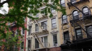 New York 'ta bir caddenin statik görüntüsü, ikonik yangın merdivenlerini ve bulutlu gökyüzünün altındaki tuğla cephelerini vurguluyor..