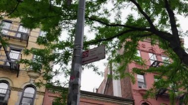 New York 'un bir sokak köşesinin statik çekimi, park yasağı işareti ve bulutlu gökyüzünün altında tarihi tuğla binalar.