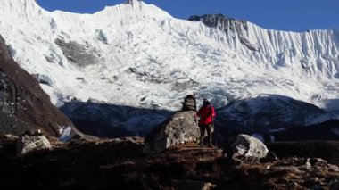 Yalnız bir yürüyüşçü Nepal 'in Himalayalarında görkemli bir buzulun önünde duruyor, sabahın erken saatlerindeki dingin güzelliği yakalıyor..