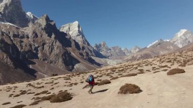 Nepal 'deki Himalayalar' ın çorak arazisinde gezinen bir yürüyüşçünün insansız hava aracı görüntüsü, Görkemli kar örtülü dağları ve uzak güzelliği vurguluyor..