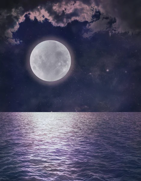 Beautiful Romantic Full Moon Ocean Reflection - dark blue sky with pink tinged clouds and a low full moon over rippling water ideal for astrology or spiritual pagan theme background