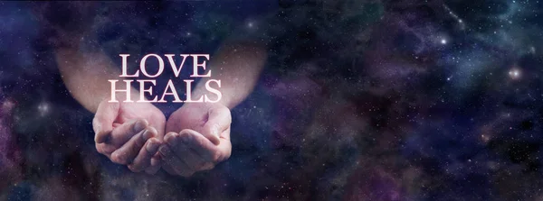 Love Heals and is the answer to every problem template - male hands gently cupped and the words LOVE HEALS floating above emerging from a celestial deep space night sky background with copy space