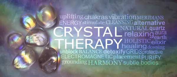 Crystal therapy word cloud on rustic rainbow background - selection of rainbow light infused tumbled healing stones against a dark multicoloured background with a relevant word cloud