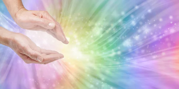 Reiki Rainbow Distant Healing Starlight Message Background - Male Reiki Master Healer with cupped hands sending quantum energy against beautiful rainbow energy field background and copy space