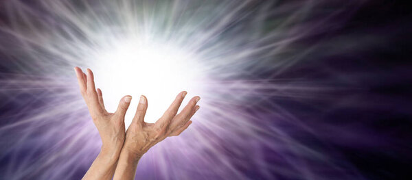 Reiki Master Therapist Lightworker sending you Healing - female open palm hands reaching into a burst of bright white light against a dark background with copy space                             