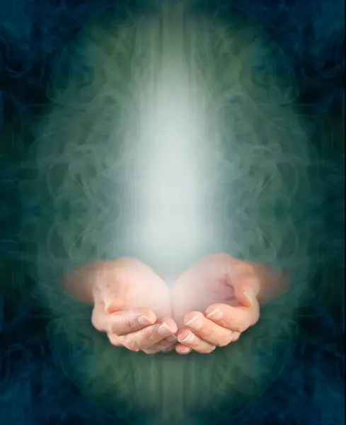 Sending love and blessing heart healing vibes concept - female cupped hands in ethereal green oval with rising white energy  and dark blue border with copy space all around ideal for spiritual wall art