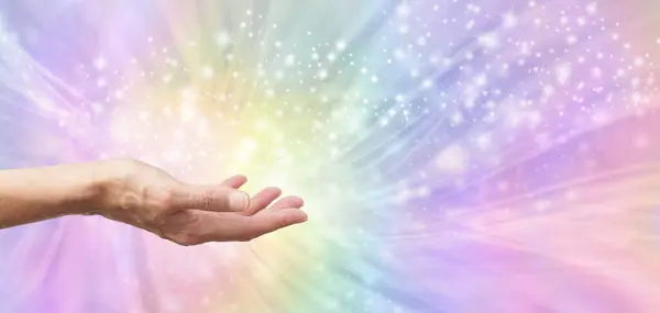 Reiki Rainbow Distant Healing Starlight Message Background - Female Reiki Master Healer with open hand sending quantum energy against beautiful rainbow energy field background and copy space