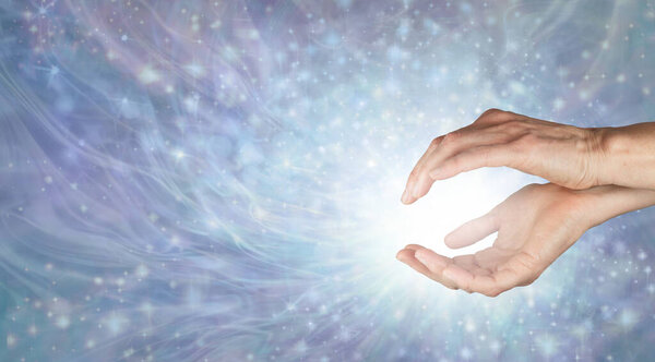 Приглашение насладиться нежной целебной энергией - женские руки с белым светом и красивым излучающим прохладное бледно-голубое энергетическое поле из искр с копировальным пространством для духовного послания