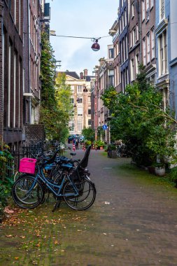Hollanda 'da Amsterdam' ın dar sokaklarına parketmiş bisikletler. Ara sokakta pembe sepetli bisiklet.