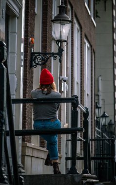 Amsterdam, Hollanda: 13 Ekim 2017: Merdivenlerde oturan kırmızı şapkalı bir kız